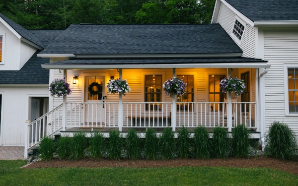Wraparound porch of the Mile Away farmhouse illuminated at dusk